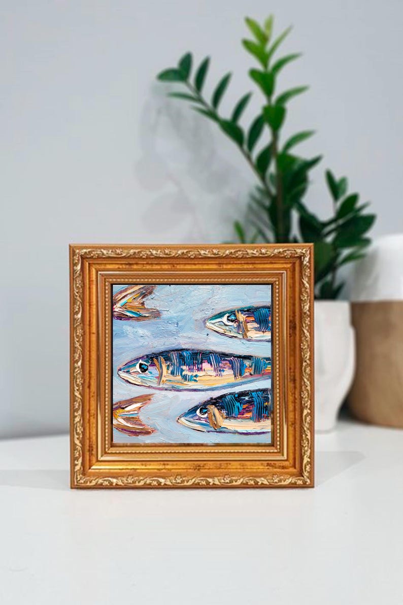 May include: Square framed oil painting featuring a school of fish. The fish are painted with blue, orange, and yellow brushstrokes against a light blue background. The frame is gold with ornate detailing.