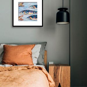 May include: A framed artwork featuring an abstract painting of several fish in shades of blue, yellow, and orange. The artwork is displayed on a gray wall above a bed with orange and gray bedding. A black pendant light hangs from the ceiling.