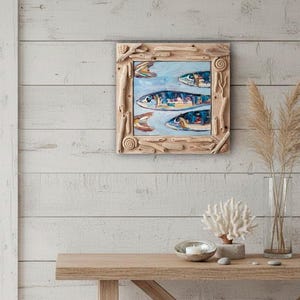 May include: A framed painting of four fish swimming in a light blue sea. The fish are painted with blue, yellow, and orange details. The frame is made of natural driftwood pieces.