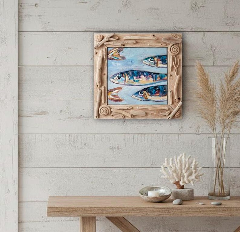 May include: A framed painting of four fish swimming in a light blue sea. The fish are painted with blue, yellow, and orange details. The frame is made of natural driftwood pieces.