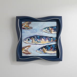 May include: An oil painting of several fish in shades of blue, yellow, and brown, set against a light blue background. The artwork is framed in a navy blue, wavy-edged frame with a silver inner border. The painting has a textured, impressionistic style.
