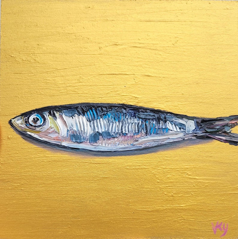 A small, silver fish painted on a gold background. The fish has a blue and white pattern on its body and a black eye.