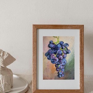 May include: An oil painting of a cluster of dark purple grapes with green stems, rendered with visible brushstrokes. The artwork is displayed in a rectangular wooden frame with a natural grain finish, showcasing a textured, painterly style.