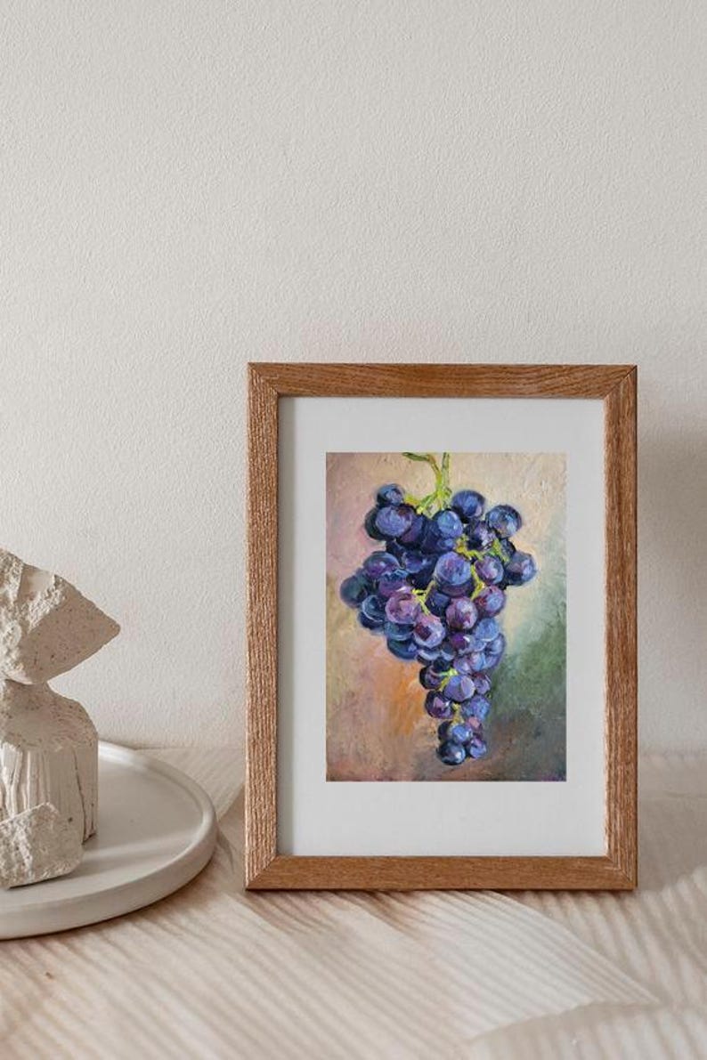 May include: An oil painting of a cluster of dark purple grapes with green stems, rendered with visible brushstrokes. The artwork is displayed in a rectangular wooden frame with a natural grain finish, showcasing a textured, painterly style.