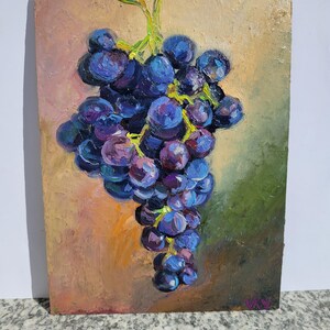 Oil painting of a bunch of grapes. The grapes are a deep purple color, with highlights of blue and pink. The background is a blend of orange, green, and brown hues, creating a warm and inviting feel. The painting is on a rectangular panel.