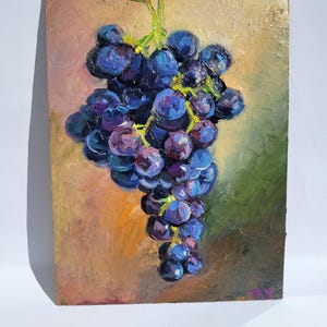May include: Oil painting of a bunch of grapes. The grapes are a deep blue-purple color, with highlights of lighter purple. The background is a blend of green, brown, and orange hues, creating a warm and inviting atmosphere. The painting is on a rectangular panel.