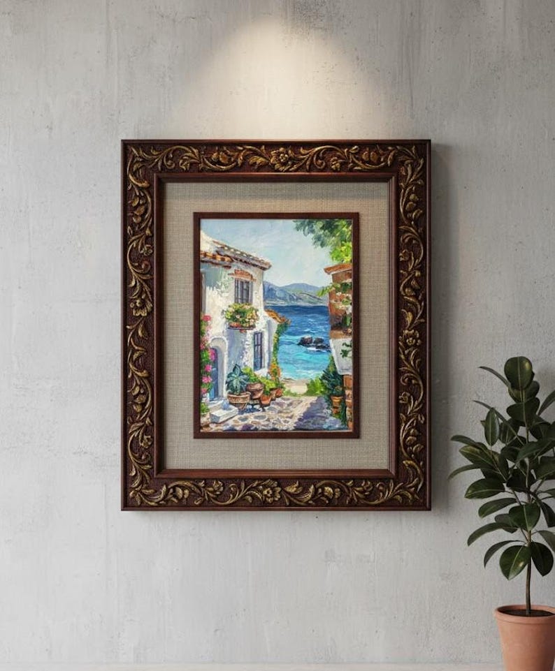 May include: A framed oil painting depicting a coastal Mediterranean scene with white buildings, potted plants, and a blue sea. The artwork is encased in a dark brown, ornate, carved wooden frame with a textured beige matting surrounding the image.
