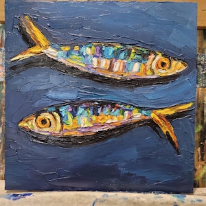 May include: An oil painting on canvas featuring two fish swimming in opposite directions against a dark blue background. The fish are rendered with thick, textured impasto brushstrokes in vibrant shades of yellow, orange, blue, and purple.