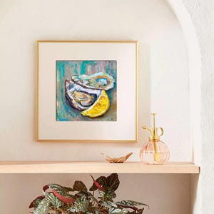 May include: Square framed artwork featuring an oil painting of two oysters and a lemon slice. The painting has a teal, blue, and brown background. The artwork is displayed on a wooden shelf with a plant in a white pot.