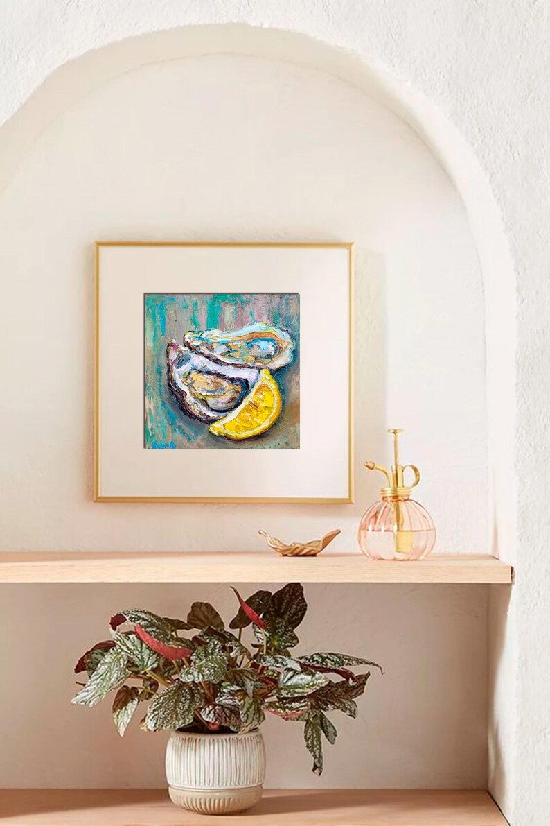 May include: Square framed artwork featuring an oil painting of two oysters and a lemon slice. The painting has a teal, blue, and brown background. The artwork is displayed on a wooden shelf with a plant in a white pot.