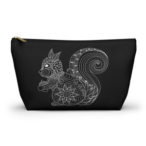 May include: Black zippered pouch with a white line drawing of a squirrel with intricate details. The squirrel is holding a nut in its paws.