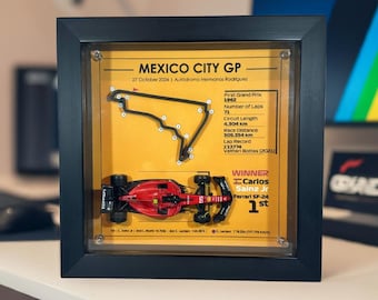 May include: A framed print of the Mexico City Grand Prix race track with a miniature red race car. The print includes the race date, track name, and winner information. The winner is Carlos Sainz Jr. in a Ferrari SF-24.