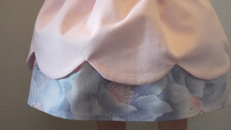 以下が含まれることがあります： ピンクのフリルのあるスカートで、青い花柄の裏地が付いています