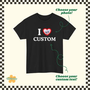 May include: Black t-shirt with the text "I CUSTOM" in white. The "I" is above a red heart with a cartoon character inside. The shirt has a round neck and short sleeves. The image includes the text "Choose your photo!" and "Choose your custom text!"