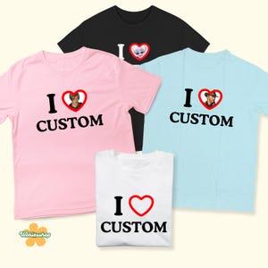 May include: A collection of t-shirts in various colors, including pink, black, and light blue. Each shirt features the text "I &hearts; CUSTOM" with a heart graphic. Some hearts contain images.