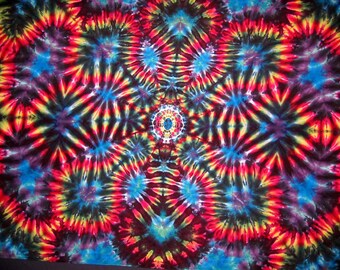 Könnte beinhalten: Ein farbenfrohes Batik-Muster mit einem zentralen Mandala-Design in Rot-, Gelb-, Blau- und Schwarztönen.
