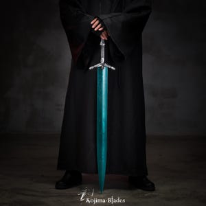 May include: A person wearing a black robe holds a long, teal-colored sword with a silver hilt. The sword has a crossguard with three points.