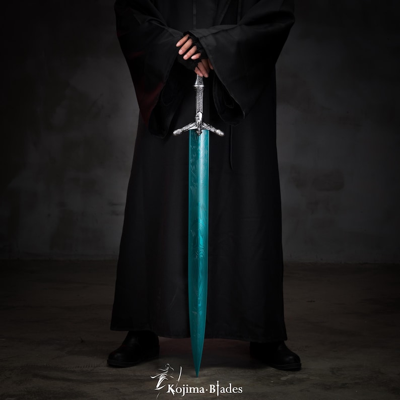 May include: A person wearing a black robe holds a long, teal-colored sword with a silver hilt. The sword has a crossguard with three points.