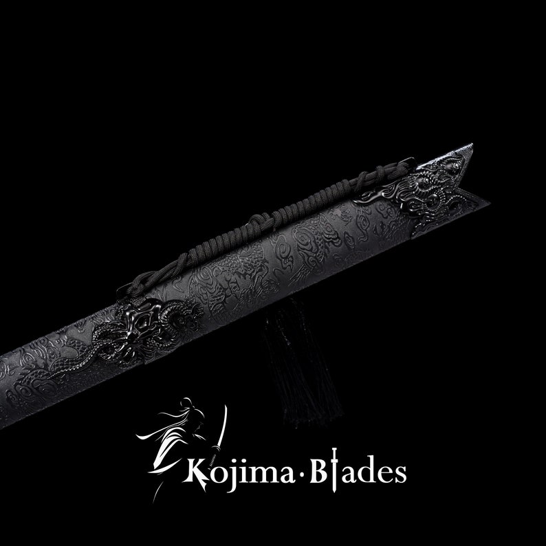 May include: Black katana sword scabbard with a dragon design and black cord. The scabbard is made of metal and has a textured surface. The cord is tied around the scabbard and has a tassel at the end. The scabbard is on a black background. "Kojima Blades" is printed in white on the bottom of the image.