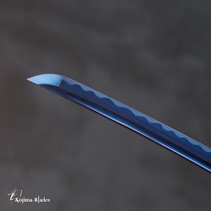 Pu&ograve; includere: Primo piano della punta di una lama di katana blu e viola.