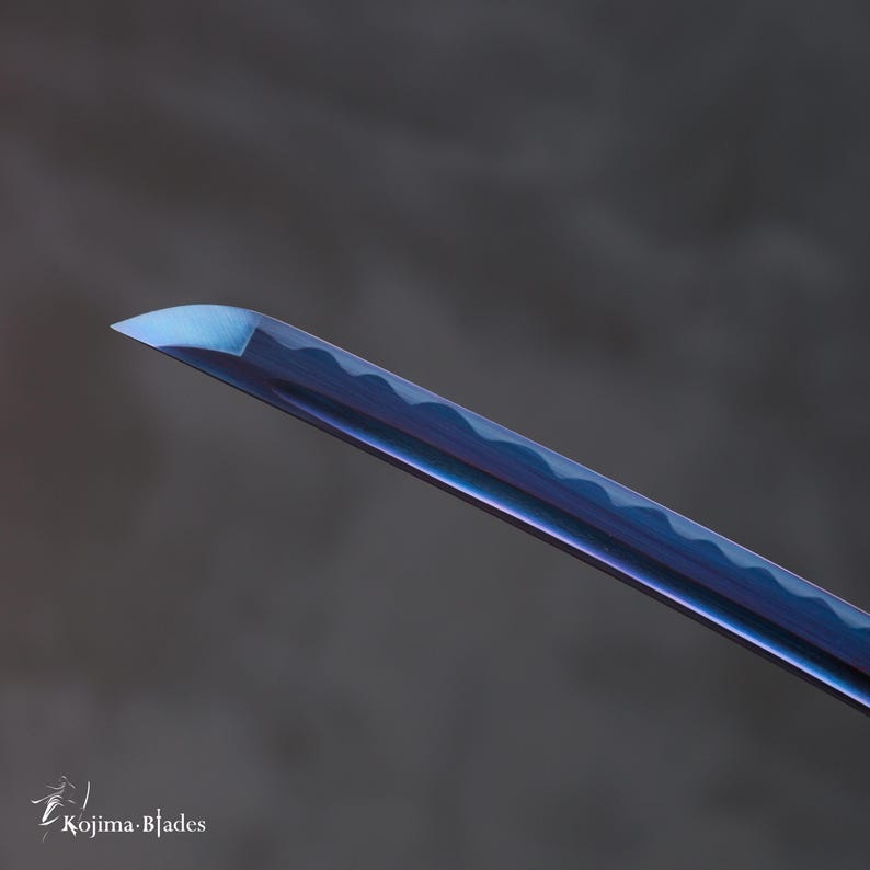 Pu&ograve; includere: Primo piano della punta di una lama di katana blu e viola.