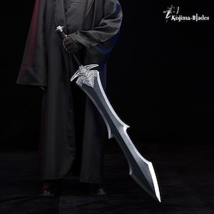 May include: A person in a black robe holds a large, silver sword with a detailed, ornate hilt. The sword has a black blade with a sharp point.