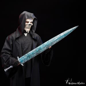 Puede incluir: Una persona con una t&uacute;nica negra con capucha y una m&aacute;scara de calavera blanca sostiene una espada larga, azul y plateada con dise&ntilde;os intrincados. La espada tiene una punta afilada y una empu&ntilde;adura plateada.