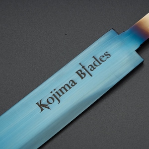 May include: A close-up of a blue steel blade with the text "Kojima Blades" etched into the surface.