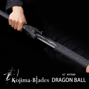 Może przedstawiać: Czarny miecz katana z rękojeścią w kształcie smoka i czarną pochwą z wzorem smoka. Miecz ma 109 cm długości i jest oznaczony jako "Kojima Blades DRAGON BALL 43" Katana".