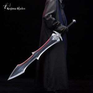 May include: A black sword with a red blade and intricate silver detailing on the hilt. The sword is held by a person wearing a black coat.