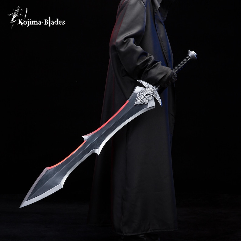 May include: A black sword with a red blade and intricate silver detailing on the hilt. The sword is held by a person wearing a black coat.