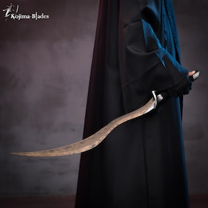 May include: A person wearing a black robe holds a curved, silver-colored sword with a dark, aged blade. The sword has a unique, slightly curved design.