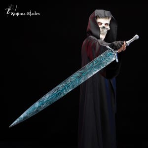 Puede incluir: Una persona con una t&uacute;nica negra con capucha y una m&aacute;scara de calavera sostiene una espada larga de plata con una hoja azul y verde. La espada tiene intrincados dise&ntilde;os grabados en la hoja.