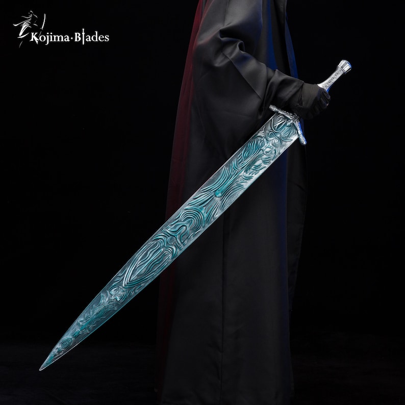 Puede incluir: Una espada larga de plata con una hoja de patr&oacute;n azul y verde. La espada est&aacute; sostenida por una persona que lleva una capa negra.