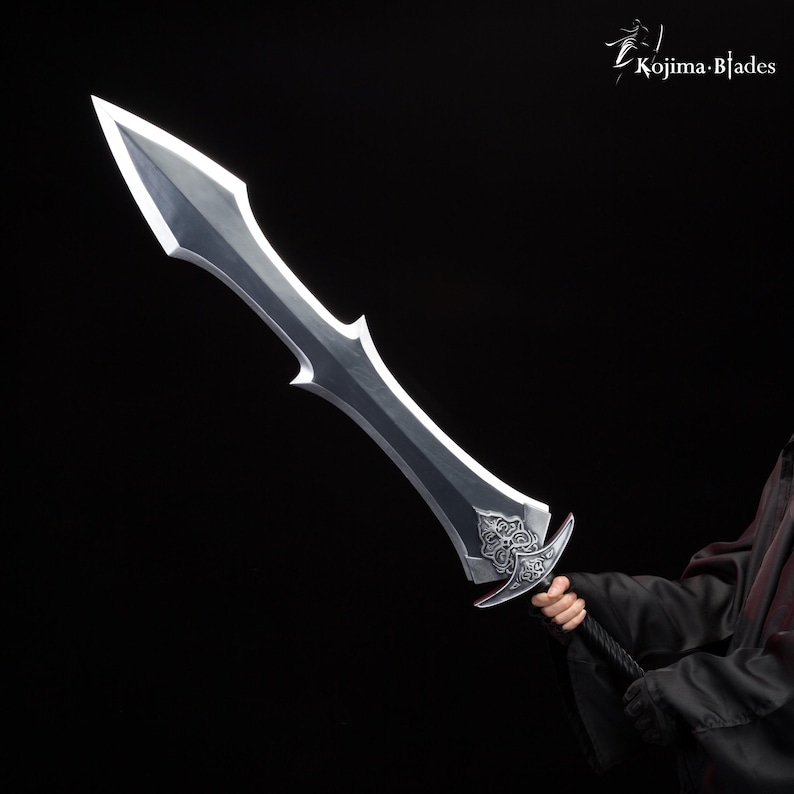 May include: A silver sword with a decorative handle and a sharp point. The sword is held by a person wearing a black robe.