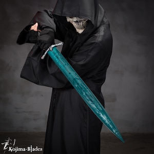 May include: A person wearing a black hooded robe holds a teal-colored sword with intricate designs. The sword has a silver hilt and a sharp point.