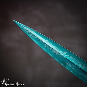 May include: Close-up of the tip of a teal-colored sword blade with intricate etched designs.