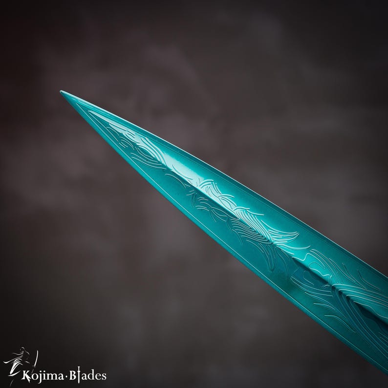 May include: Close-up of the tip of a teal-colored sword blade with intricate etched designs.