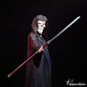 Op de afbeelding: Een lang, recht zwaard met een rode handgreep en een zilveren lemmet. Het zwaard wordt vastgehouden door een persoon die een zwarte capuchonmantel en een schedelmasker draagt. Het zwaard is ongeveer 152 cm lang.