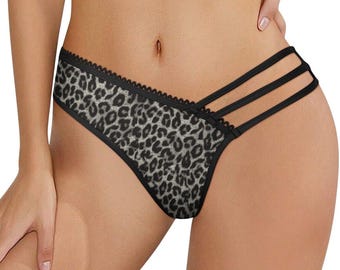 May include: A pair of underwear featuring a grey and black leopard print pattern. The garment has a scalloped black trim along the top edge and three thin black elastic straps extending from the side to the back, creating a cut-out design.
