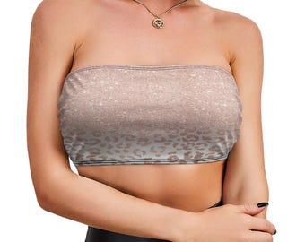 May include: A strapless tube top featuring a gradient design that transitions from a shimmering rose gold glitter texture at the top to a subtle, light-colored leopard print pattern at the bottom, constructed from a stretchy fabric material.