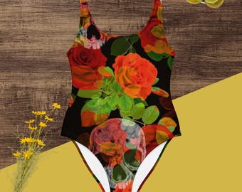 May include: A one-piece swimsuit featuring a black background with a vibrant floral and skull pattern. The design includes bright red and orange roses, green leaves, and detailed skull illustrations integrated throughout the fabric.