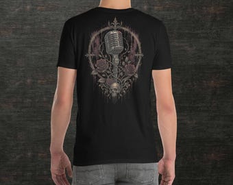 May include: A black short-sleeve t-shirt featuring a graphic on the back. The design displays a vintage-style microphone centered within an ornate, thorny circular frame, accompanied by dark roses and a skull at the base with dripping paint effects.