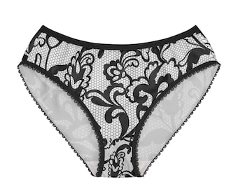 May include: Black and white underwear featuring a detailed lace-inspired floral pattern over a fine mesh background. The garment has a solid black waistband and black scalloped trim along the leg openings, creating a distinct contrast.