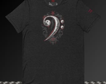 May include: A charcoal gray short-sleeve t-shirt featuring a central graphic of a white bass clef symbol surrounded by intricate black filigree, red rose accents, and a small star icon. The shirt has a crew neckline and a small red logo on the sleeve.