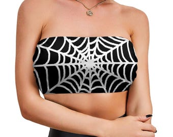 May include: A strapless tube top featuring a bold, high-contrast graphic print of a white spider web pattern set against a solid black background. The garment is designed with a straight neckline and a fitted silhouette that covers the torso.