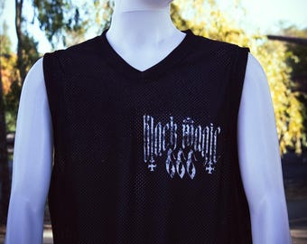 May include: Black sleeveless mesh shirt with a V-neck. The shirt features the text "Black Magic 666" in a gothic font on the chest. The shirt is displayed on a mannequin.