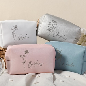 Puede incluir: Cuatro neceseres personalizados con dise&ntilde;os florales y nombres: Sophia, Daphne, Brittany y Nicola. Las bolsas son de color blanco, plateado, rosa y azul.