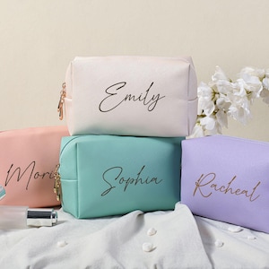 Puede incluir: Cuatro bolsas de cosm&eacute;ticos personalizadas en diferentes colores. Las bolsas est&aacute;n hechas de un material suave y texturizado y tienen un cierre de cremallera. Las bolsas est&aacute;n etiquetadas con los nombres "Emily", "Sophia", "Rachel" y "Morgan".