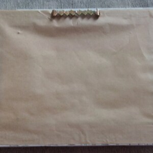 May include: A plain white picture frame with a brown paper backing and a metal hanging hook on the top.